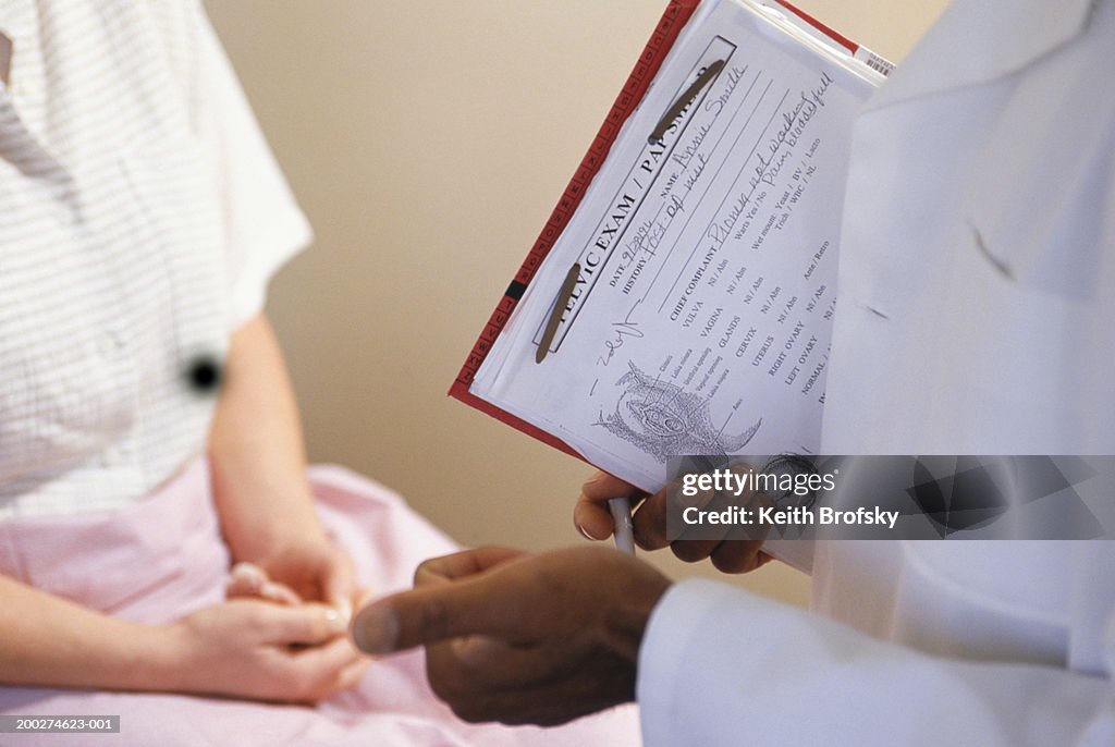 Gynaecologist talking to patient, mid section
