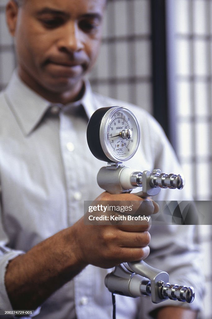 Man holding dynamometer in right hand
