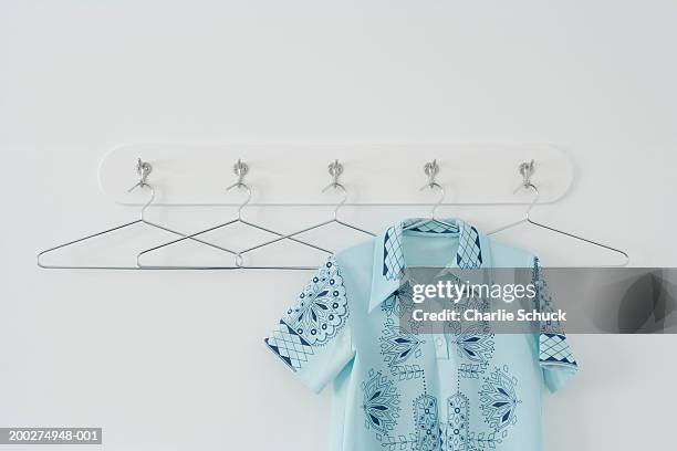 shirt hanging amongst empty hangers on row of hooks - coat rack stock pictures, royalty-free photos & images