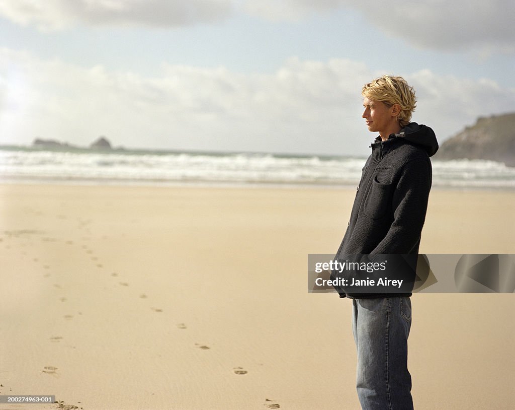 Young man standing on beach, side view