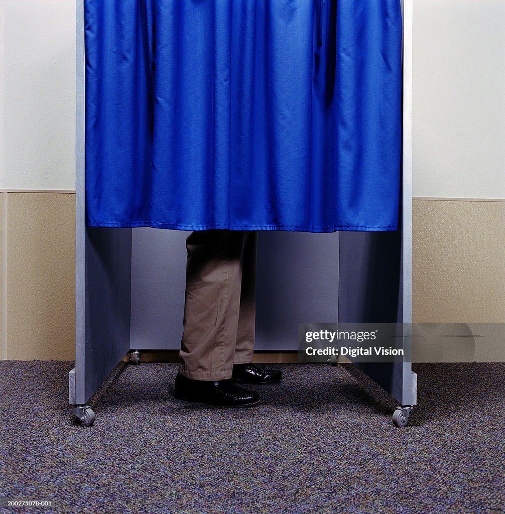 Man standing behind curtain in booth, low section