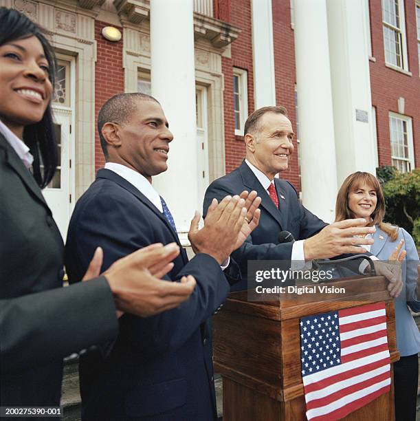 man making speech at podium outside building, associates applauding - presidente fotografías e imágenes de stock