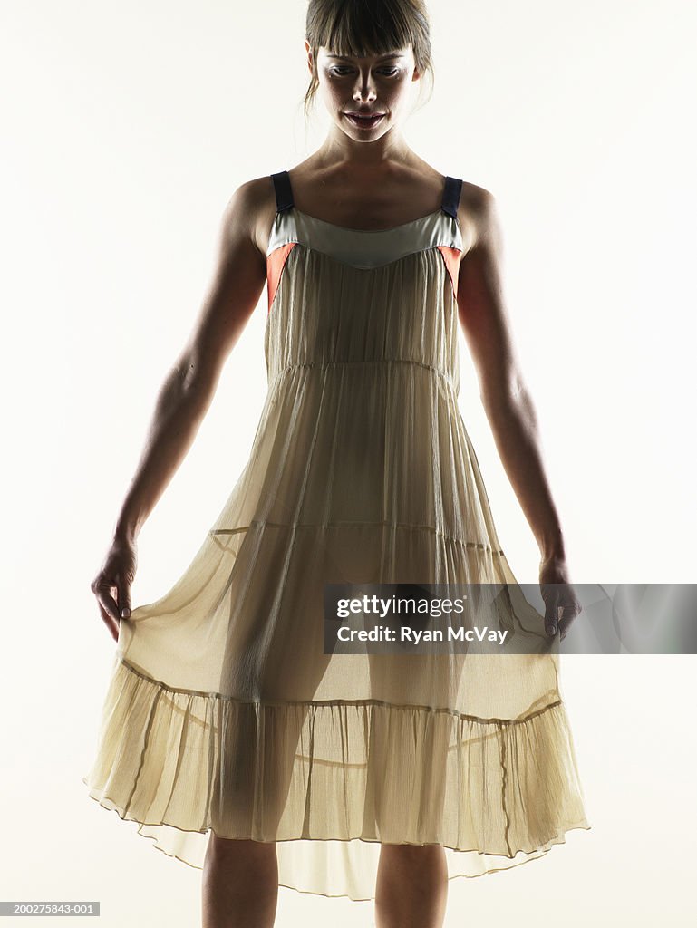 Woman lifting dress from both sides, looking down