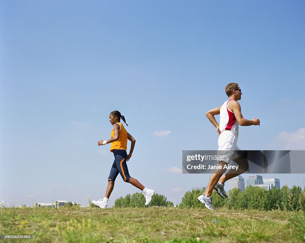 Man and woman running in opposite directions through field