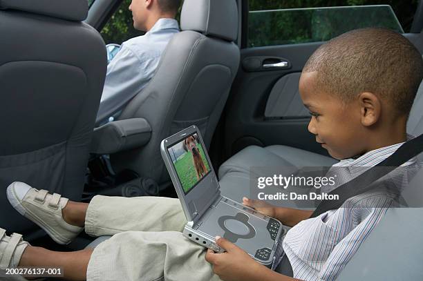 father and son (5-7) in car (focus on boy using portable dvd player) - dvd player in car stock pictures, royalty-free photos & images