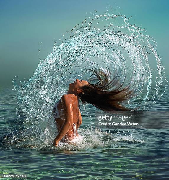 woman wearing bikini tossing wet hair back in sea, laughing, side view - huvudet bakåt bildbanksfoton och bilder