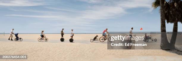 people riding bikes, roller skating on beach (digital composite) - bike beach stock-fotos und bilder