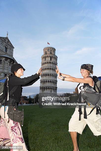 italy, pisa, two women pretending to hold up the leaning tower of pisa - perspective artificielle photos et images de collection