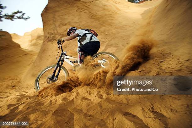 man mountain biking down sandstone cliff, low angle view - 踩登山車 個照片及圖片檔