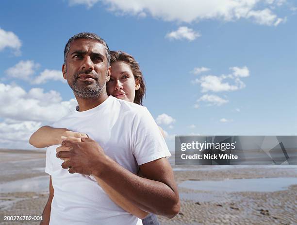 couple on beach, woman with arms around man - mature indian couple stock pictures, royalty-free photos & images