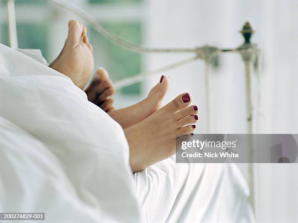 couple lying in bed, feet sticking out of covers, low section - indian female feet foto e immagini stock