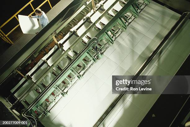 man looking at paper next to paper cutting machine at pulp mill - paper industry stock pictures, royalty-free photos & images