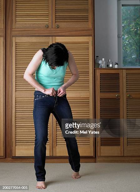 woman in bedroom struggling to fasten jeans button - knäppa knappar bildbanksfoton och bilder