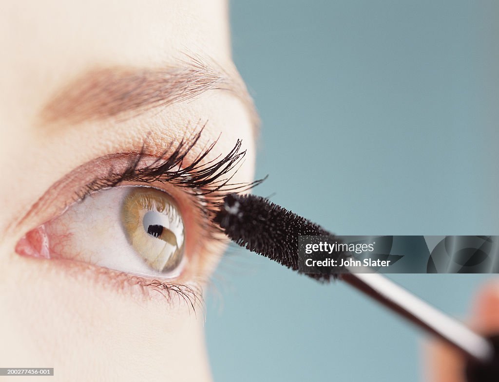 Young woman applying mascara, close-up of eye