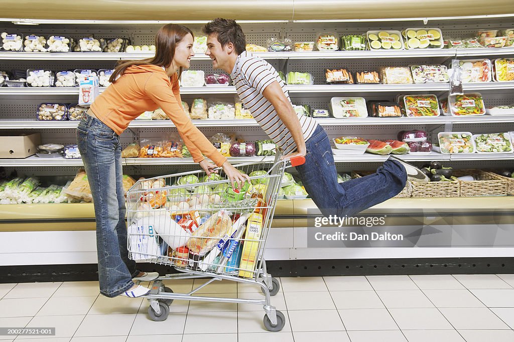 Young Couple Riding Trolley In Supermarket Smiling Profile High-Res ...