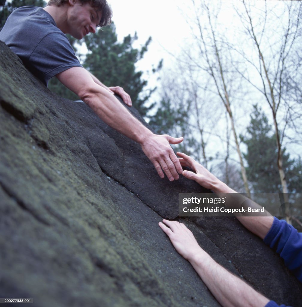 Rock climber extending hand to fellow climber