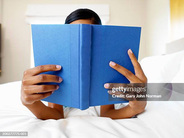 woman reading book in bed - black woman no face stock-fotos und bilder