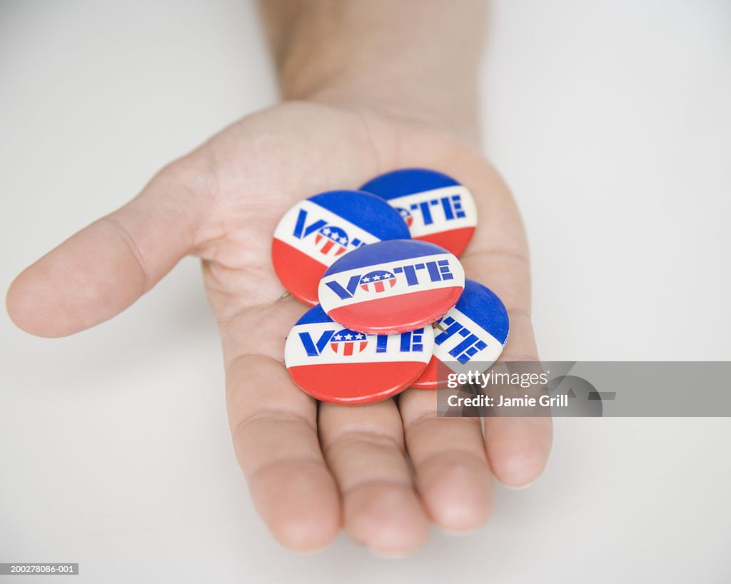 Man holding 'VOTE' buttons, close-up