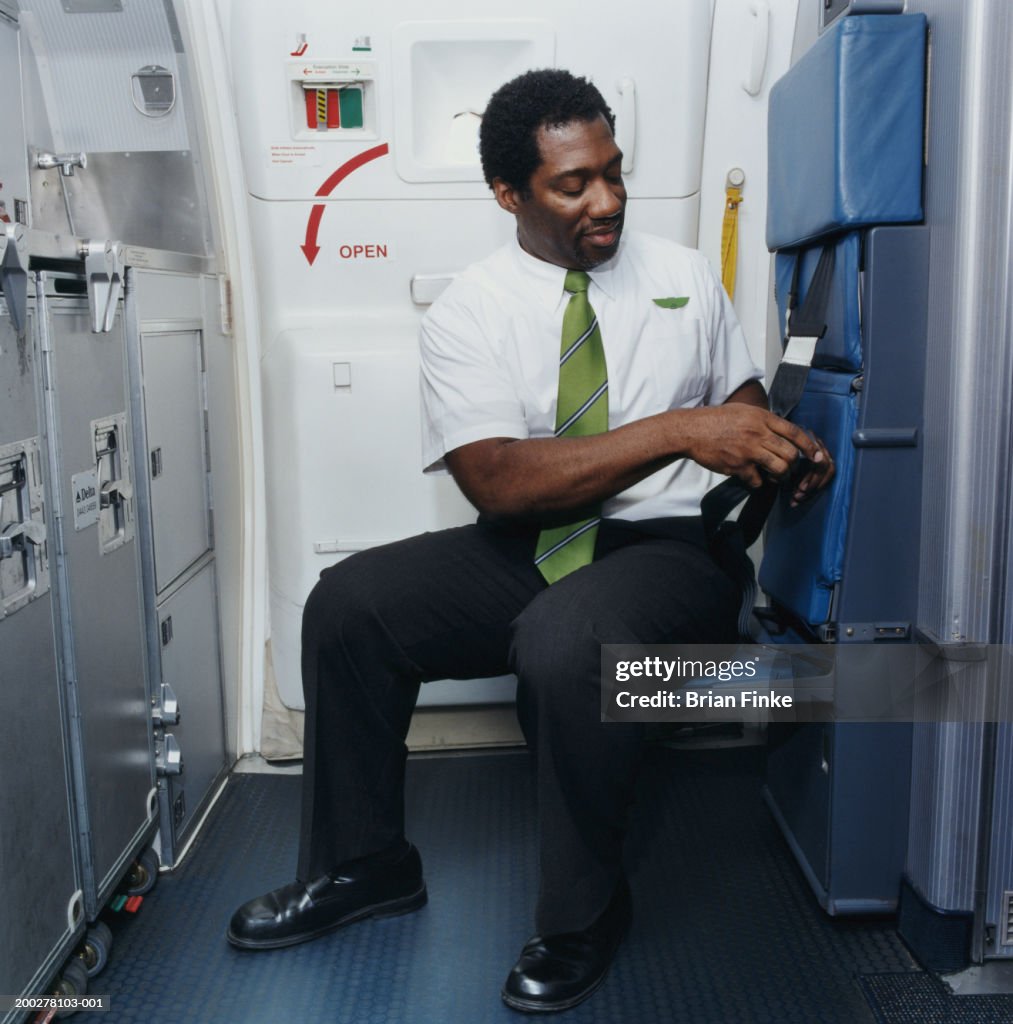 Flight attendant fixing seat belt on airplane