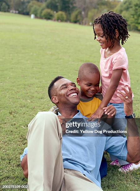 father and children (5-9) laughing in park - two kids playing with hose stock-fotos und bilder