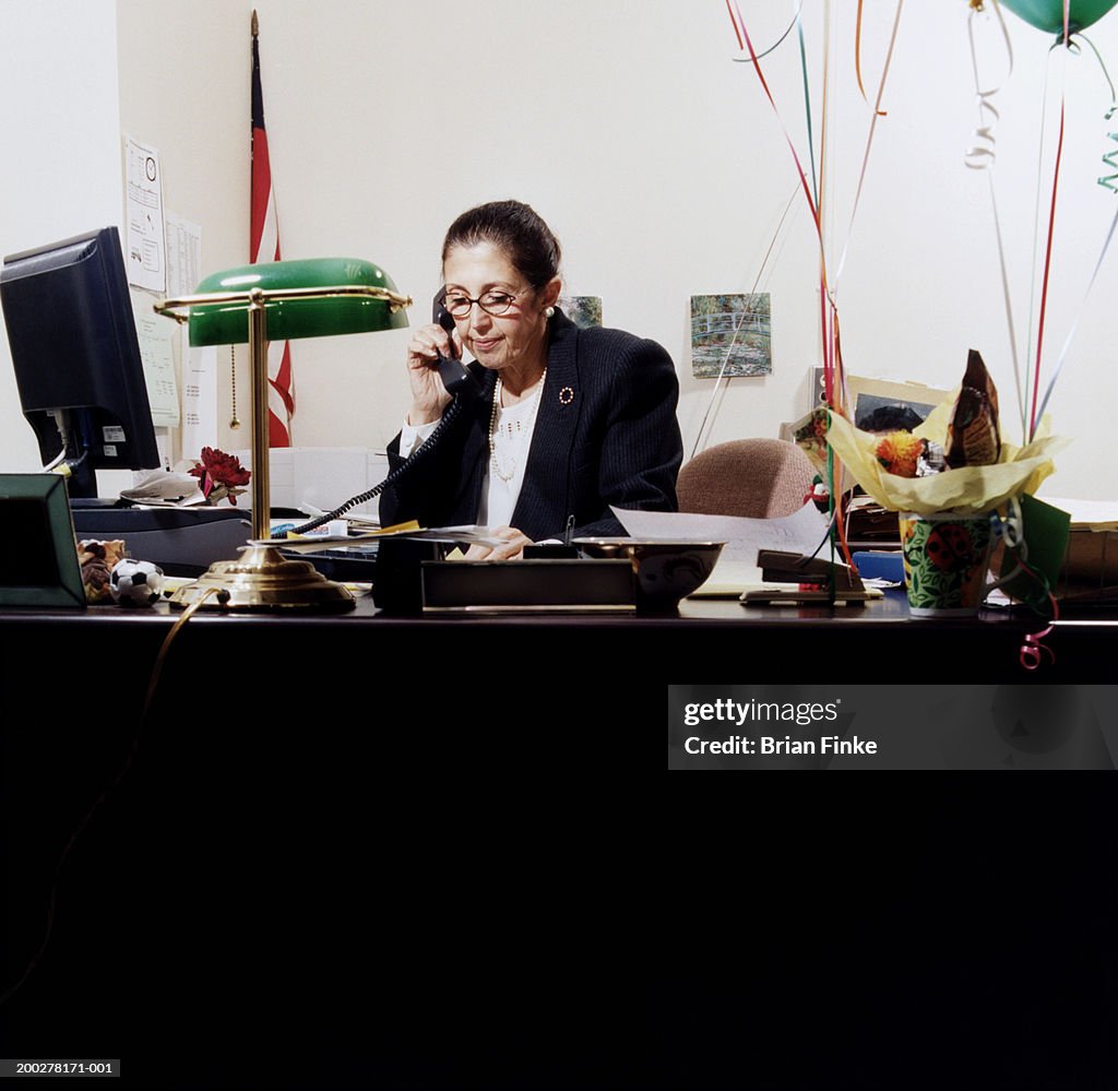 Mature woman at desk using telephone