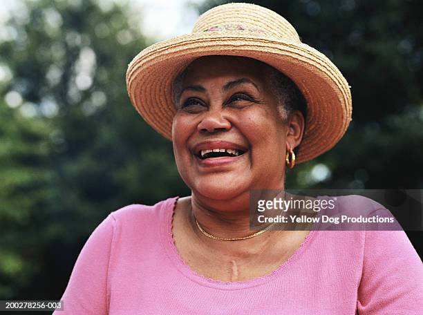 senior woman wearing straw hat, smiling - black hat stockfoto's en -beelden