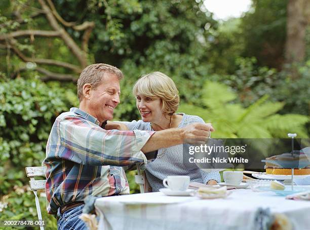 couple at garden table, man pouring tea - theepot stockfoto's en -beelden