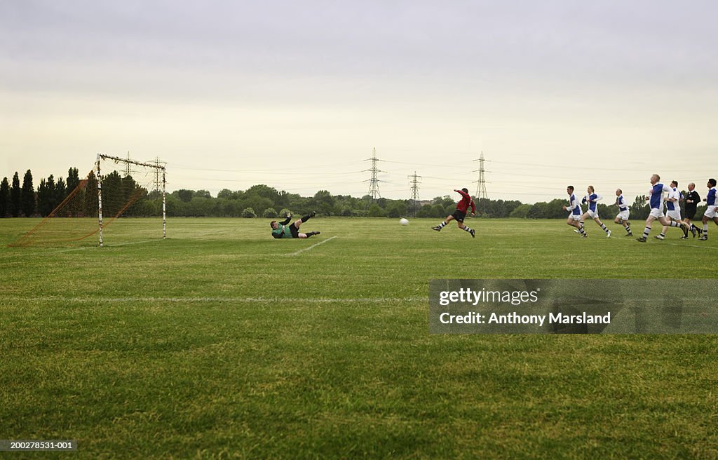 Mixed football match, opposing team chasing player towards goal