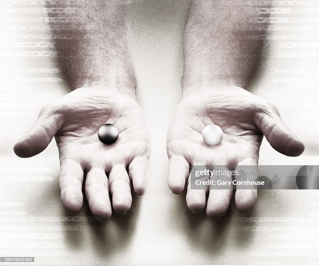 Man with white and black balls on palm of hands, close-up