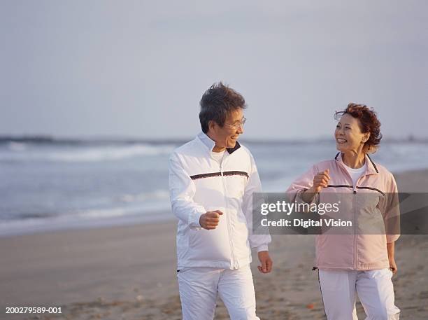 senior couple walking on beach, smiling - japanese ethnicity stock pictures, royalty-free photos & images