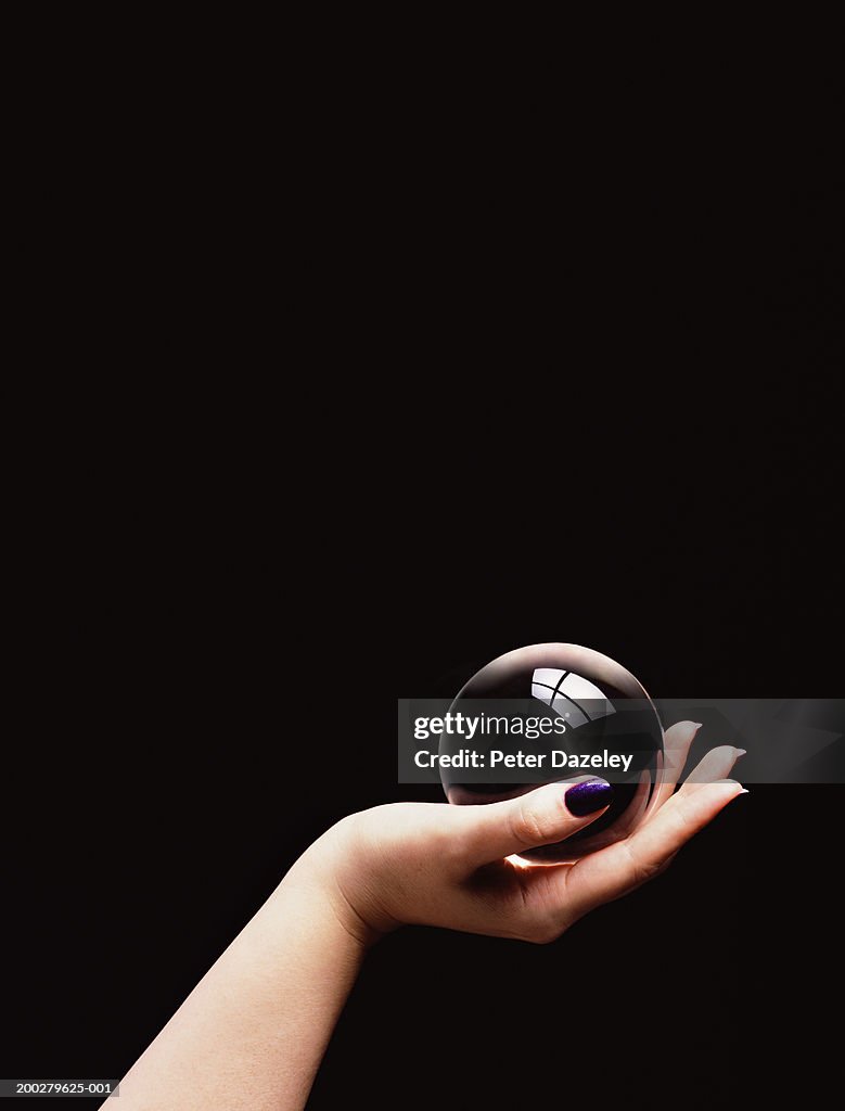 Woman holding crystal ball in palm of hand