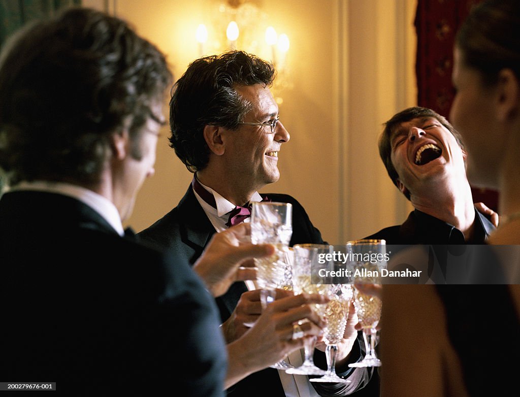 Adults wearing formal attire, toasting champagne glasses