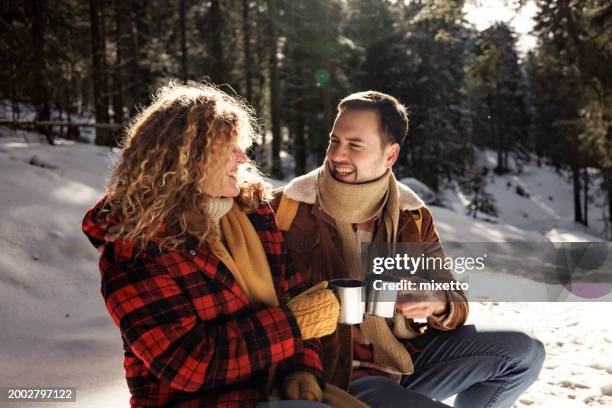 giovane coppia allegra che gode il caffè in una soleggiata giornata invernale in montagna - bevanda calda foto e immagini stock