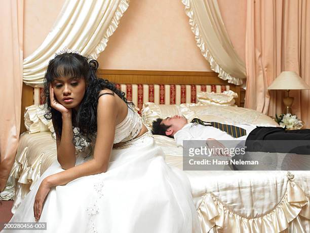 bride sitting at edge of bed, groom sleeping - sad groom stock pictures, royalty-free photos & images