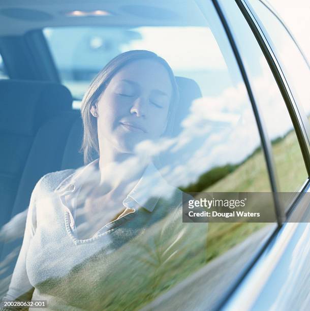 young woman in passenger seat of car, eyes closed, smiling - sleeping in car stockfoto's en -beelden