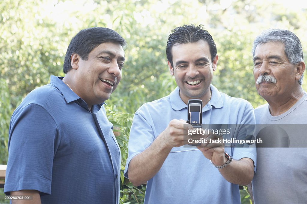 Three men looking at a mobile phone