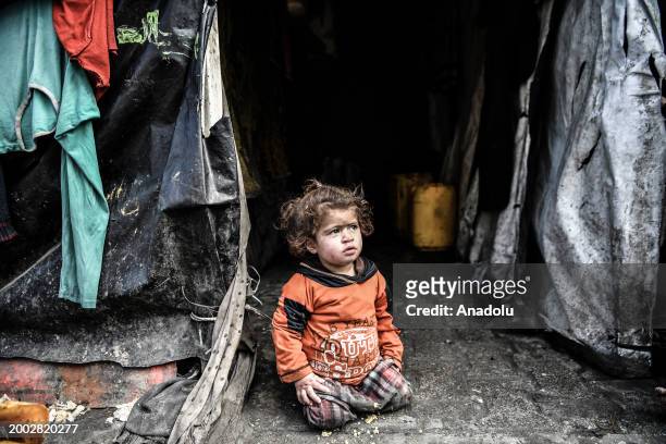 Palestinian child sits near makeshift tent as Palestinians, trying to live in makeshift tents they set up, are viewed in Rafah, Gaza on February 14,...