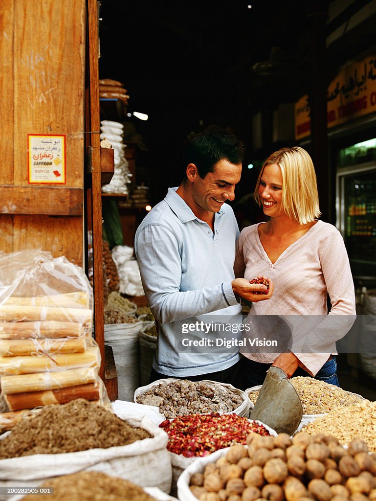 Couple at spice store, man with handful of dried chillis, smiling