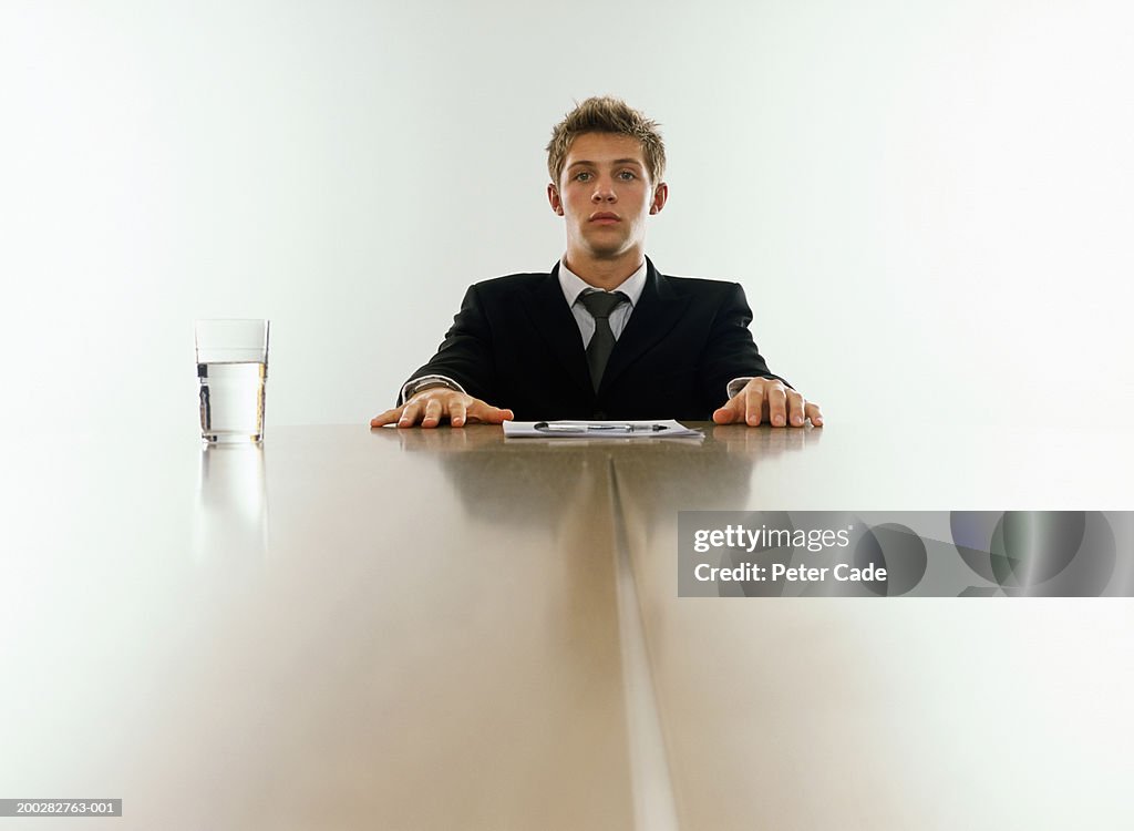 Young businessman sitting at end of table, portrait