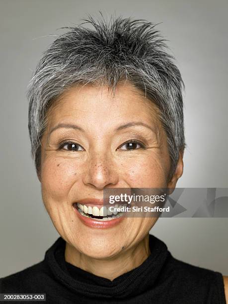 mature woman wearing black top, smiling - spitzhaarfrisur stock-fotos und bilder