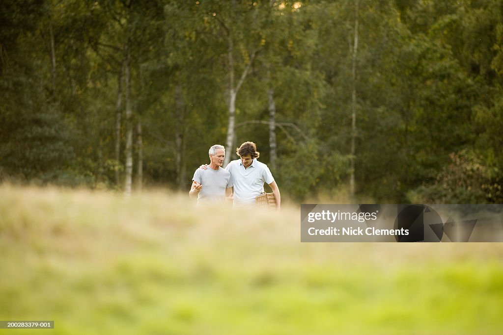 Mature man and adult son walking up hill, man with arm around father