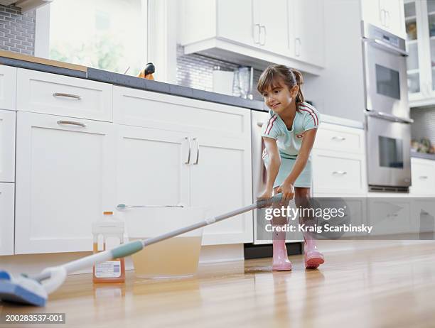 girl (6-8) cleaning kitchen floor with mop, smiling, low angle view - kitchen mop stock pictures, royalty-free photos & images