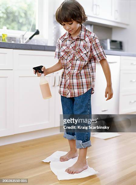 boy (5-7) drying kitchen floor with paper towel under feet, smiling - hochgekrempelte hose stock-fotos und bilder