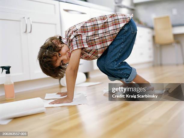 boy (5-7) polishing floor with paper towel under hands and feet - kitchen paper stock pictures, royalty-free photos & images