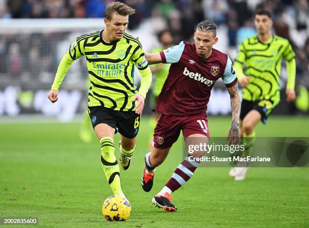 Martin Odegaard of Arsenal runs with the ball from Kalvin Phillips of West Ham United during the Premier League match between West Ham United and...