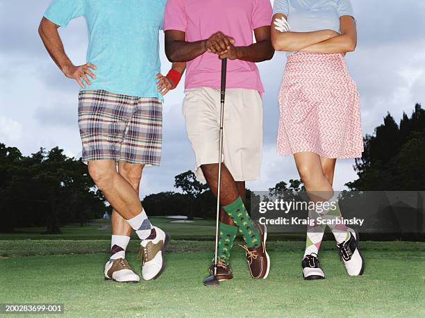 three golfers standing in row on golf course, low section - rosa shorts stock-fotos und bilder