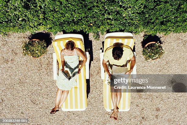 couple lying on sunbeds reading, overhead view - strand liegen stock-fotos und bilder