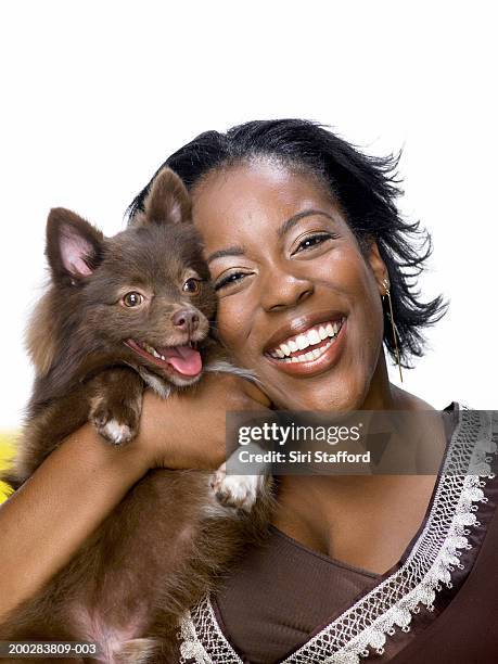 junge frau hält kleinspitz hund, lächeln - woman holding dog studio stock-fotos und bilder