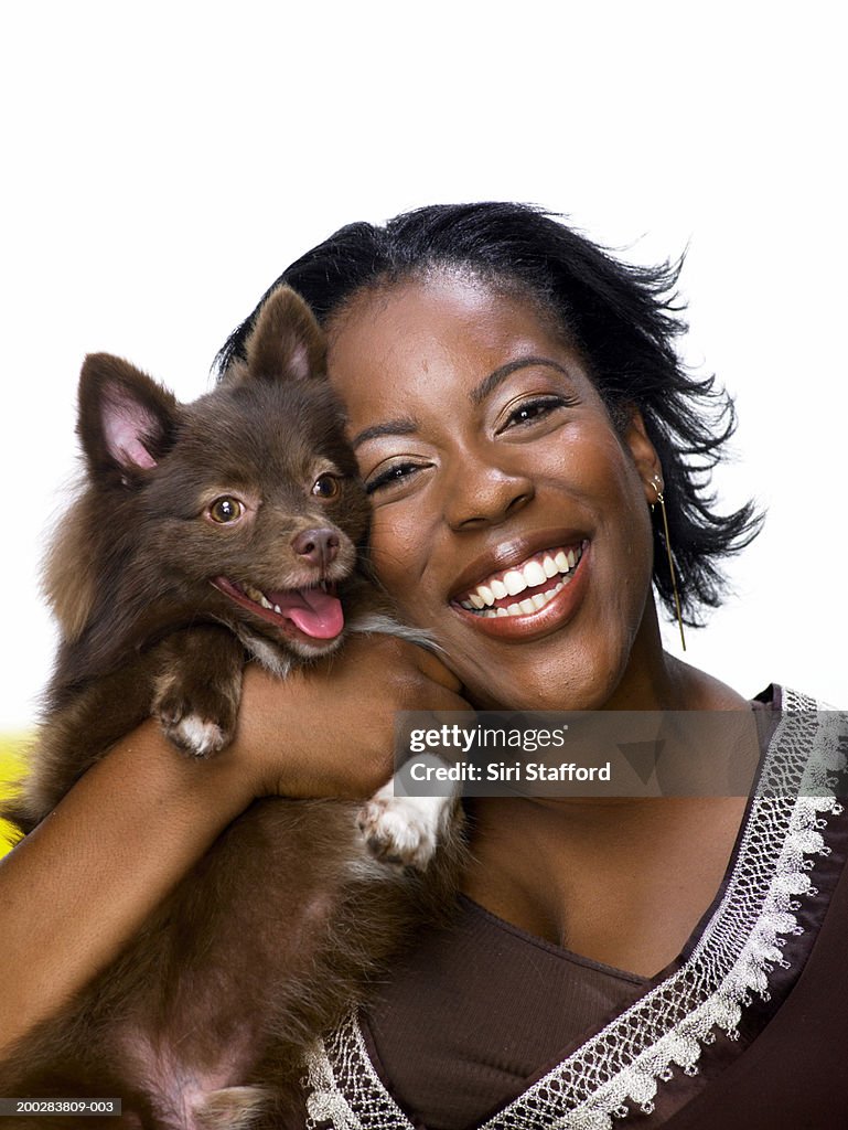 Young woman holding Pomeranian dog, smiling