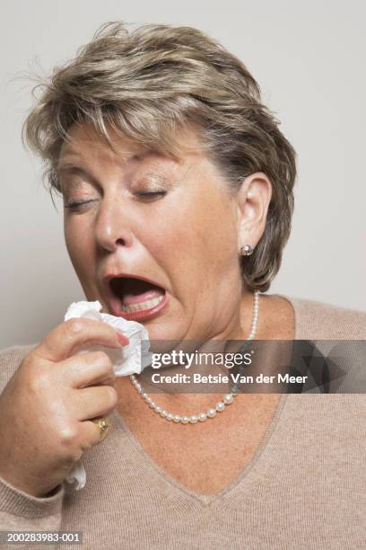 mature woman holding handkerchief about to sneeze, close-up - くしゃみ ストックフォトと画像